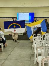 Duas pessoas mascaradas segurando, respectivamente, as bandeiras de Pernambuco e de Triunfo.